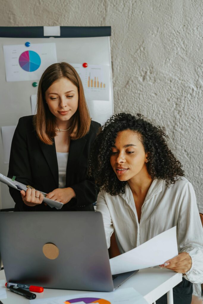 Two confident women working together on a project in a modern office.